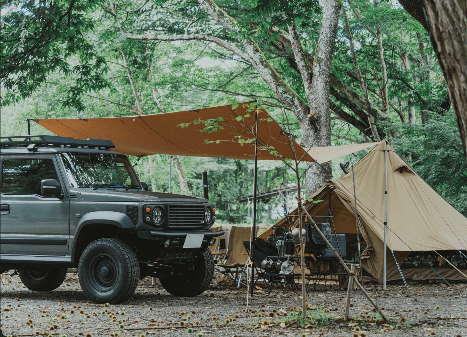 木が生い茂るキャンプ場にテントと車がある様子