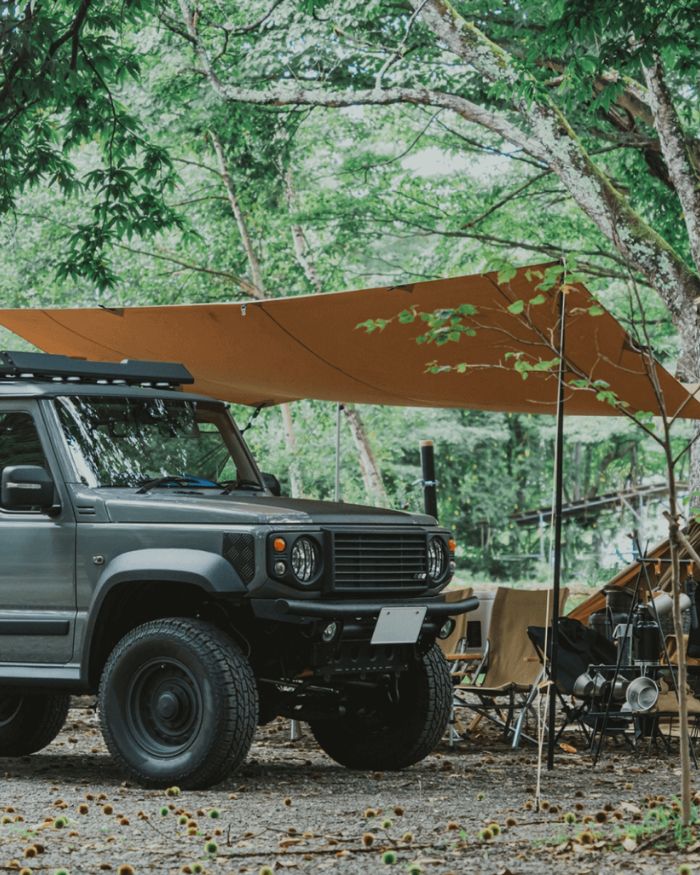 木が生い茂るキャンプ場にテントと車がある様子