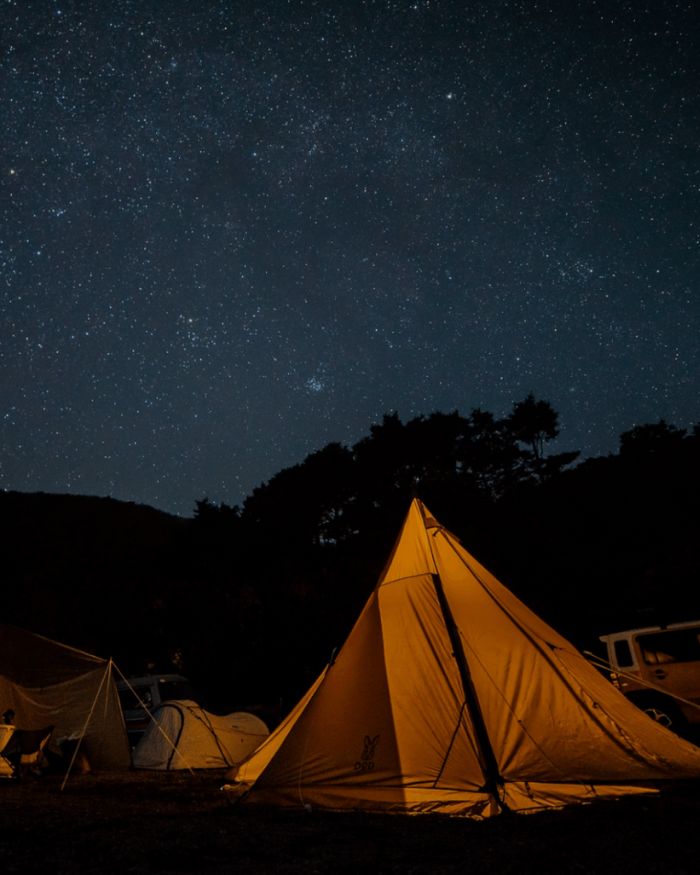 星が輝く夜空の下に複数のテントが設営されている様子