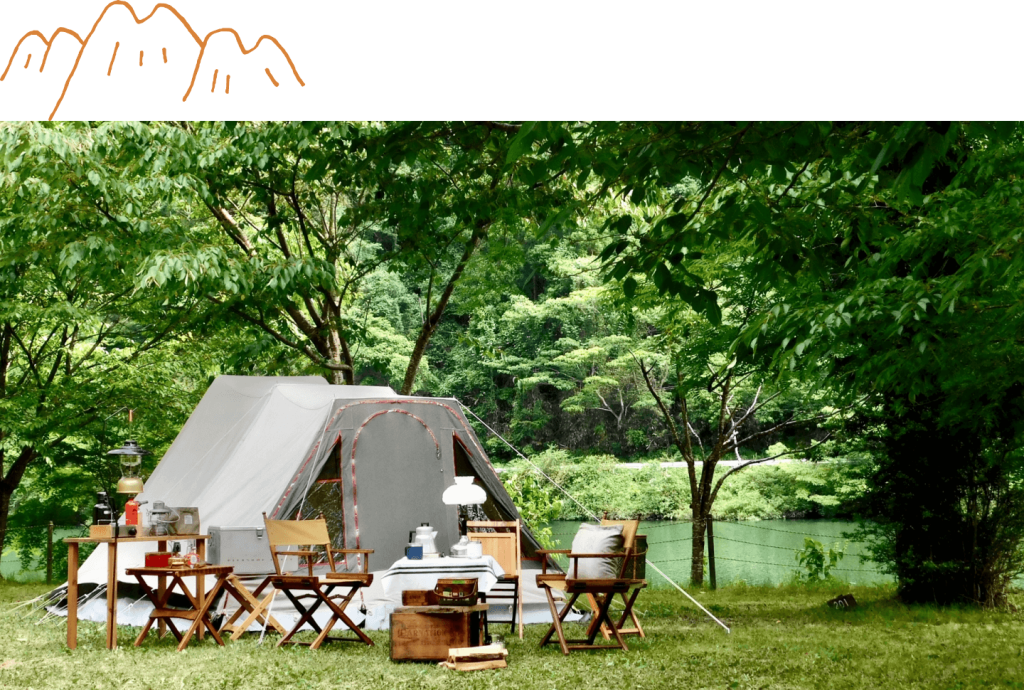 緑豊かな木々と湖を背景に白いテントと椅子・テーブルが並んでいる様子