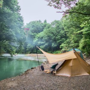 川辺のキャンプ場でテントを張っている様子