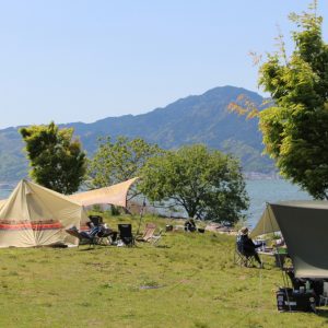 広々とした湖畔のキャンプ場でテントを張っている様子